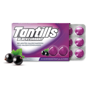 Paket mit Tantills Blackcurrant Halspastillen auf lila Hintergrund, umgeben von schwarzen Johannisbeeren und einem frischen Blatt.