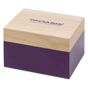 Eine schlichte Holzkiste mit hellbraunem Deckel und violettem Unterteil, beschriftet mit "TAOASIS".