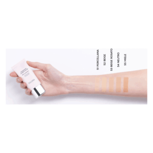 Eine Hand hält eine Tube mit dunkelrosa Verpackung, daneben sind fünf Farbproben auf dem Unterarm zu sehen.