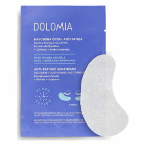 Eine blaue Verpackung mit einer Augenmaskenbeschreibung, inklusive Inhaltsstoffen wie Koffein und Hyaluron. Ein einzelner Augenpad liegt daneben.