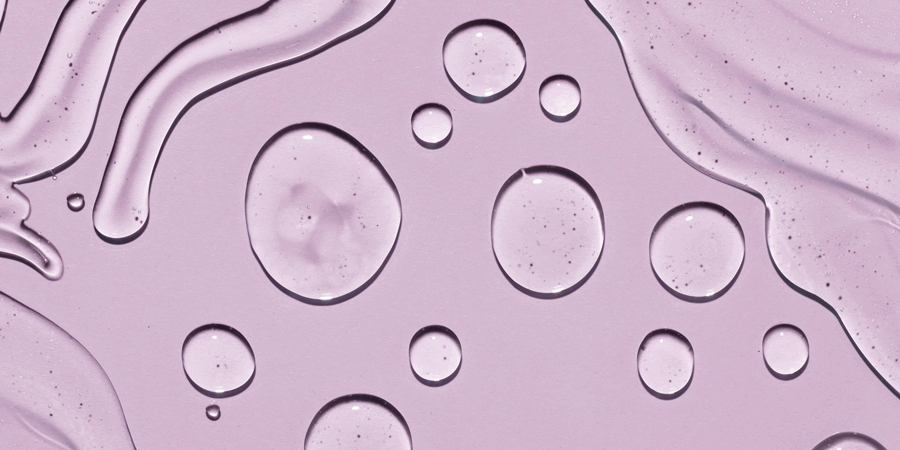 Hyaluron-web.png Transparente Wassertropfen auf einem helllila Hintergrund, mit fließenden Linien und Blasen.