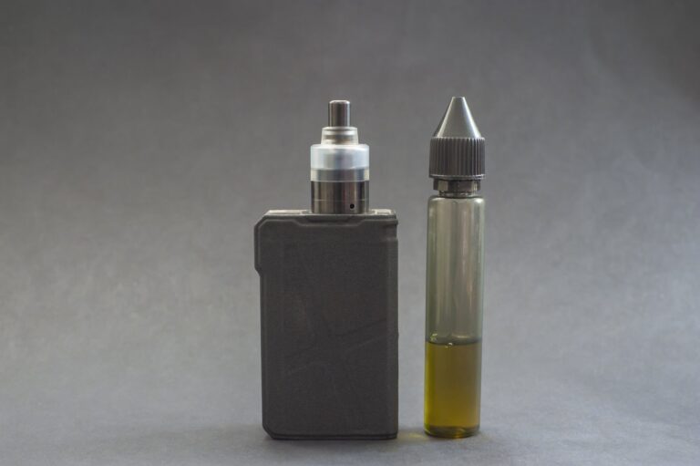 Ein Verdampfergerät links, daneben eine Flasche mit E-Liquid in einer transparenten Verpackung.