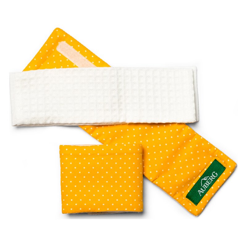 Ein gelbes Wärmekissen mit weißen Punkten und ein weißes, strukturiertes Bezugsteil daneben.