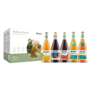 Verpackung „Wellness Woche“ von Biotta mit fünf verschiedenen Saftflaschen und einem Bild von einer Frau in der Natur.