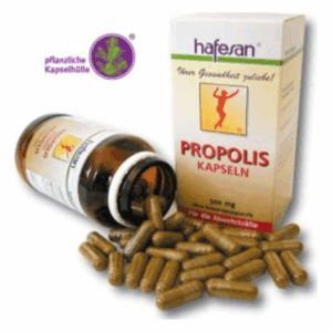 Eine Flasche mit Propolis-Kapseln steht neben einer offenen Verpackung, Kapseln liegen verstreut auf einer Fläche.