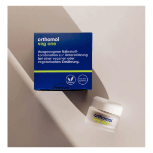 Blaue Verpackung mit der Aufschrift 'orthomol veg one', unterstützt vegane Ernährung, zusätzlich ein kleiner Behälter daneben.