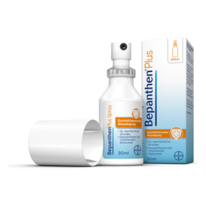 Bepanthen Plus Desinfizierendes Wundspray in einer weißen Flasche mit Sprühkopf und einer Verpackung.