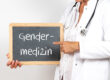 Eine Person in Arztkleidung hält eine Tafel mit der Aufschrift "Gendermedizin".