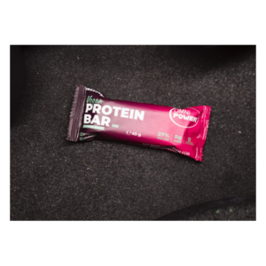 Eine vegane Proteinriegel-Verpackung in lila mit den Angaben zu Nährstoffen, auf dunklem Hintergrund.