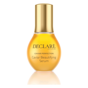 Flasche mit Caviar Beautifying Serum von DECLARÉ, orangefarben mit goldenem Deckel, reflektierender Oberfläche.